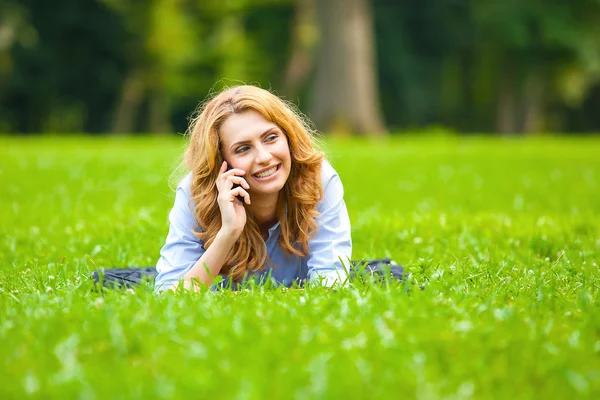 Mujer rubia hablando en el teléfono celular en hierba verde — Foto de Stock