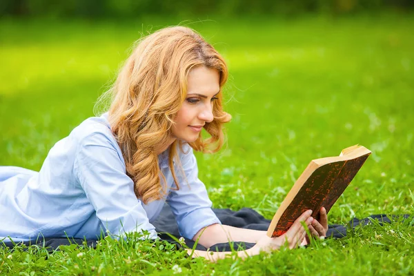 Femme couchée dans l'herbe et lisant un livre — Photo