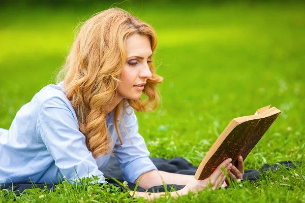 女人躺在草丛中，读一本书 — 图库照片