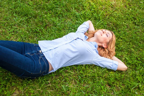 Beautiful young woman relaxing in grass — Stock Photo, Image