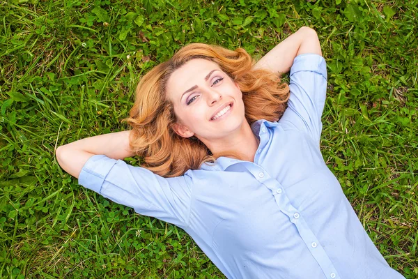 Beautiful young woman relaxing in grass — Stock Photo, Image