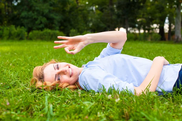 Beautiful young woman relaxing in grass — Stock Photo, Image