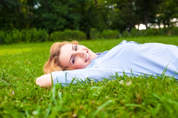 Beautiful young woman relaxing in grass — Stock Photo, Image