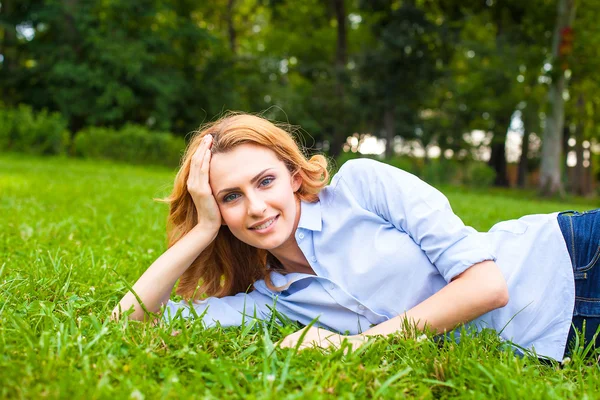 Beautiful young woman relaxing in grass — Stock Photo, Image