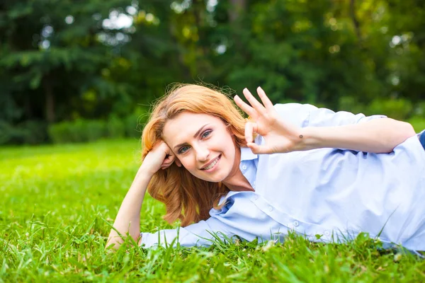 Beautiful young woman relaxing in grass — Stock Photo, Image