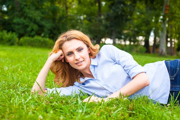 Beautiful young woman relaxing in grass — Stock Photo, Image