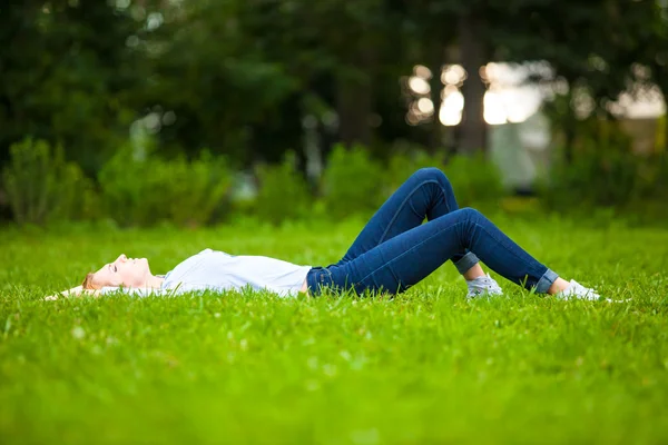 Beautiful young woman relaxing in grass — Stock Photo, Image