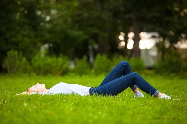 Beautiful young woman relaxing in grass — Stock Photo, Image