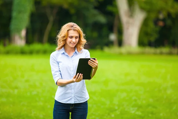 Jeune femme avec tablette dans le parc — Photo