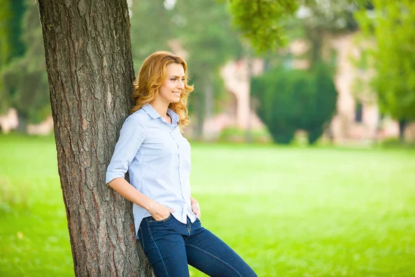 Kaunis nuori nainen seisoo puun vieressä — kuvapankkivalokuva