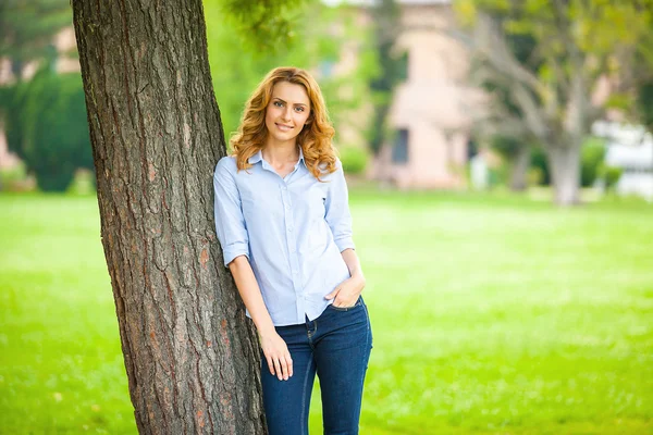 Красивая молодая женщина, стоящая рядом с деревом — стоковое фото
