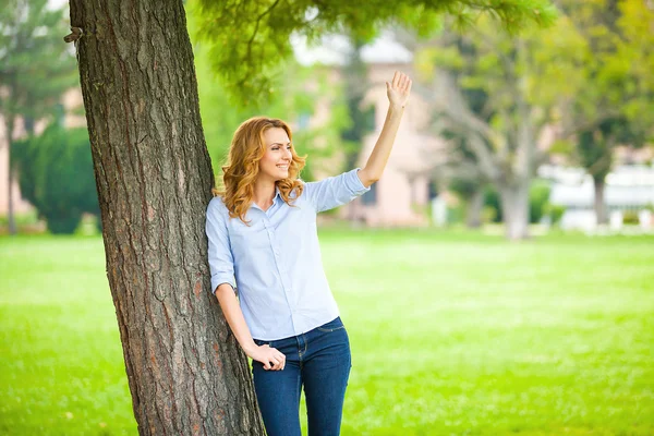 Piękna młoda kobieta stojąc obok drzewa — Zdjęcie stockowe