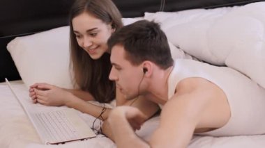 adam bir kız ile bir laptop bir yatakta yatan bir şey izliyor