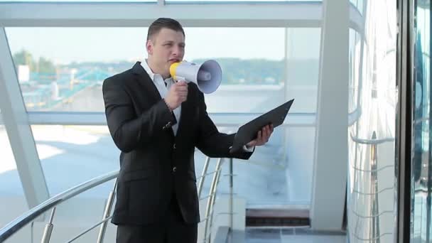 Joven empresario de la ciudad anunciando sus logros con un megáfono — Vídeo de stock