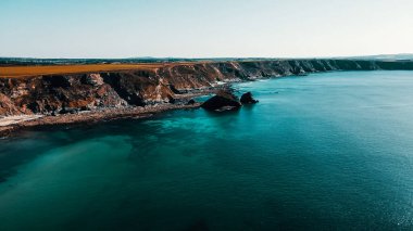 Rocks off the ocean coast line with turquoise water and dramatic cliffs Aerial view
