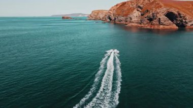 The jet ski runs in the direction of the rock on turquoise water. Aerial view.