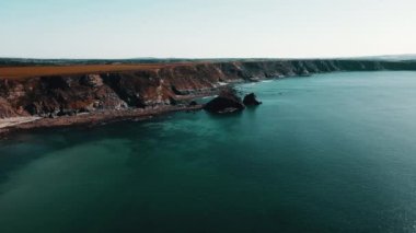 Rocks off the ocean coast line with turquoise water and dramatic cliffs Aerial view.