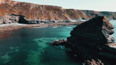 Rocks off the ocean coast line with turquoise water and dramatic cliffs Aerial view.