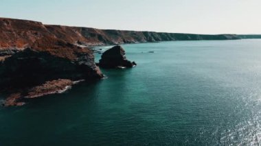 Rocks off the ocean coast line with turquoise water and dramatic cliffs Aerial view.