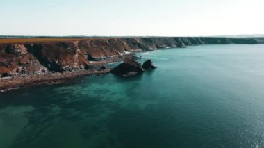 Rocks off the ocean coast line with turquoise water and dramatic cliffs Aerial view.