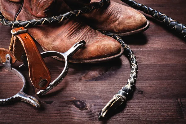 Botas de cowboy, chicote e esporas em madeira — Fotografia de Stock