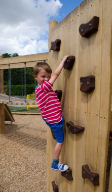 Boy on playground climbing wall clipart