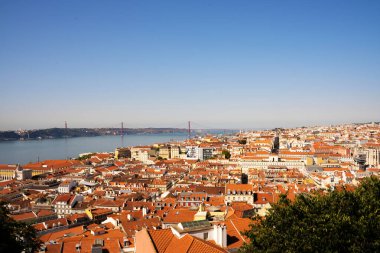 Lizbon 'da arka planda nehir olan geleneksel evlerin çatılarının panoramik manzarası