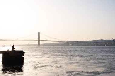 Lizbon 'da gün batımında nehre bakan bir balıkçının panormik fotoğrafı. Portekiz