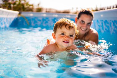 Bloinde bebek gün batımında annesiyle havuz evinde yüzmeyi öğreniyor.