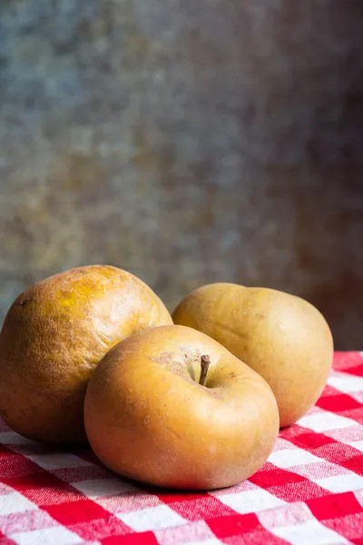 Pippin elmalarının üst görünümü, kırmızı kareli kumaş, seçici odak, gri arkaplan, dikey, kopyalama alanı ile