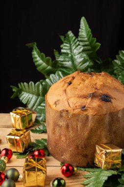 Ahşap masa üzerindeki panettone üst görünümü, Noel dekorasyonu, seçici odak, siyah arkaplan, dikey