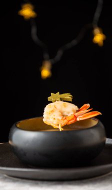 Siyah kâse karides ve somon kremalı, kırsal masada, siyah arka planda Noel ışıkları, dikey