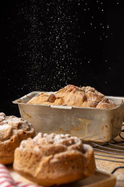 Odaklanmamış erik keki yakın plan, fırından yeni çıkmış, şeker düşmüş, seçici odak, siyah arka plan, dikey