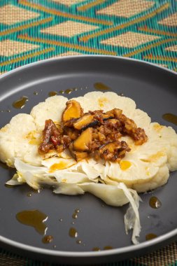 Buharda pişmiş karnabahar, jambon ve boletuslu bir tabağın üst görüntüsü, dikey olarak, kopyalama alanı ile