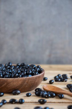 Küçük siyah fasulye (caricos) kaseli ve kaşıklı masaya yakın plan, seçici odak, gri arka plan, dikey