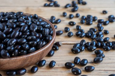 Kırsal ahşap masa üzerinde siyah fasulyeli ahşap kasenin üst görüntüsü, seçici odak, yatay, kopyalama alanı olan