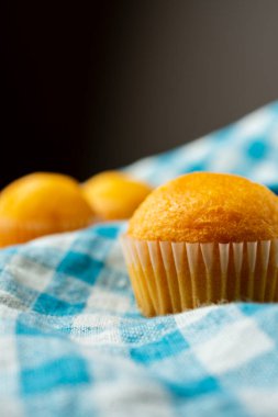 Mavi kareli bulaşık bezi, seçici odak, gri arkaplan, dikey, kopyalama alanı olan küçük kapkeklerin yakın çekimleri