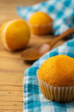 Küçük kekler ve ahşap kaşık mavi kareli bulaşık bezi ve ahşap masa, seçici odak, dikey
