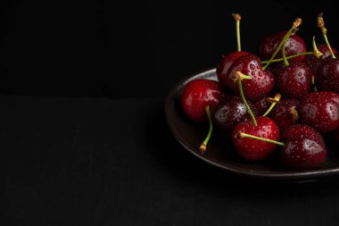 Siyah tabakta ıslak kirazların yakın plan, siyah tahta arkaplan, yatay, kopyalama alanı olan