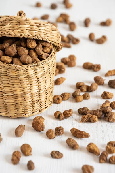 Top view of basket with tiger nuts on white table, selective focus, vertical