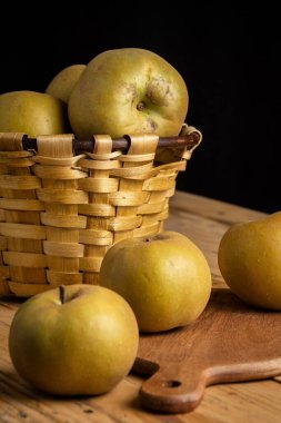Pippin elmalarının ahşap tahta üzerinde yakın plan ahşap masa ve sepet, seçici odak, siyah arkaplan, dikey