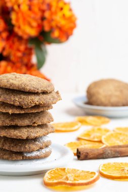 Beyaz masadaki portakal dilimleri ve çiçekli kurabiyelerin yakın plan çekimi, seçici odak, beyaz arka plan, dikey, kopyalama alanı