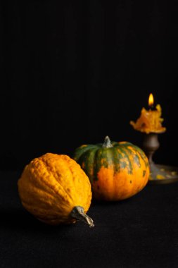 İki balkabağı ve mum yakın plan, seçici odak, masa örtüsü ve siyah arkaplan, dikey, kopyalama alanı ile