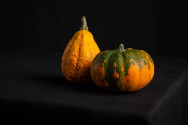 Masada cadılar bayramı için iki balkabağı yakın plan masa örtüsü ve siyah arkaplan, yatay, ciopy alan