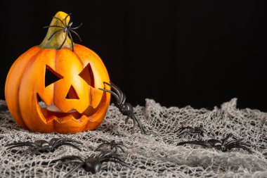 Örümcek ağına plastik örümceklerle mum koymak için gözleri ve ağzı olan seramik balkabağı görüntüsü, Cadılar Bayramı için dekorasyon, yatay