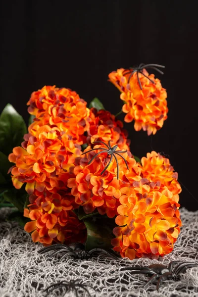 Zbliżenie Sztucznych Kwiatów Pomarańczy Plastikowymi Pająkami Stole Dekoracją Halloween Pionowe — Zdjęcie stockowe