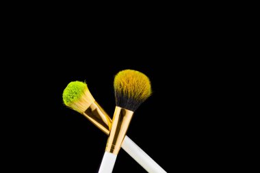 Siyah arkaplanda altın makyaj fırçası olan iki beyaz. Toz fırçası.