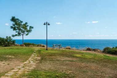 A lonely bench and a lantern on the edge of a mountain by the sea. Park by the sea, the sun
