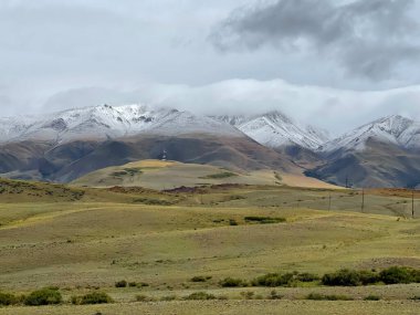 Karla kaplı dağların tepesinde bulutlar uzanıyor. Chuiskaya Steppe Kosh-Agach Bölgesi, Altai, Rusya