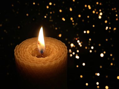 Karanlıkta yanan bir mum, ışık bokeh. Balmumundan bükülmüş güzel bir mum. Yas, üzüntü, üzüntü, kayıp ve aynı zamanda umut, sükunet, huzur ve neşe, Noel..